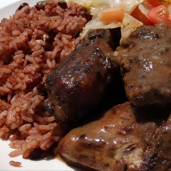 Close-up of Jamaican brown stew chicken with rice and peas, and steamed vegetables.